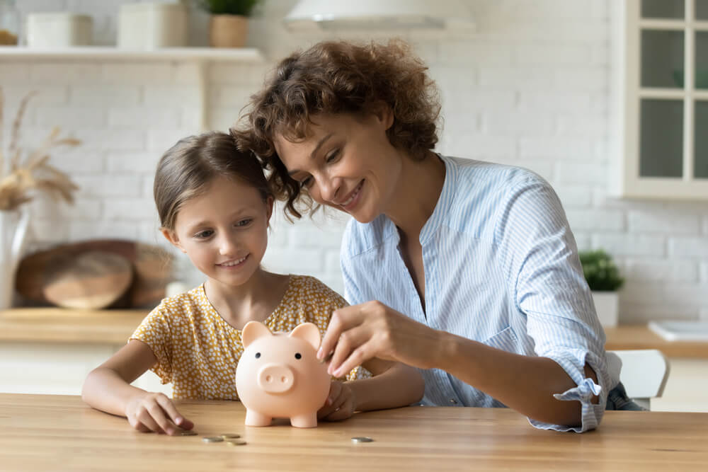 Mother and child putting money away in a piggy bank