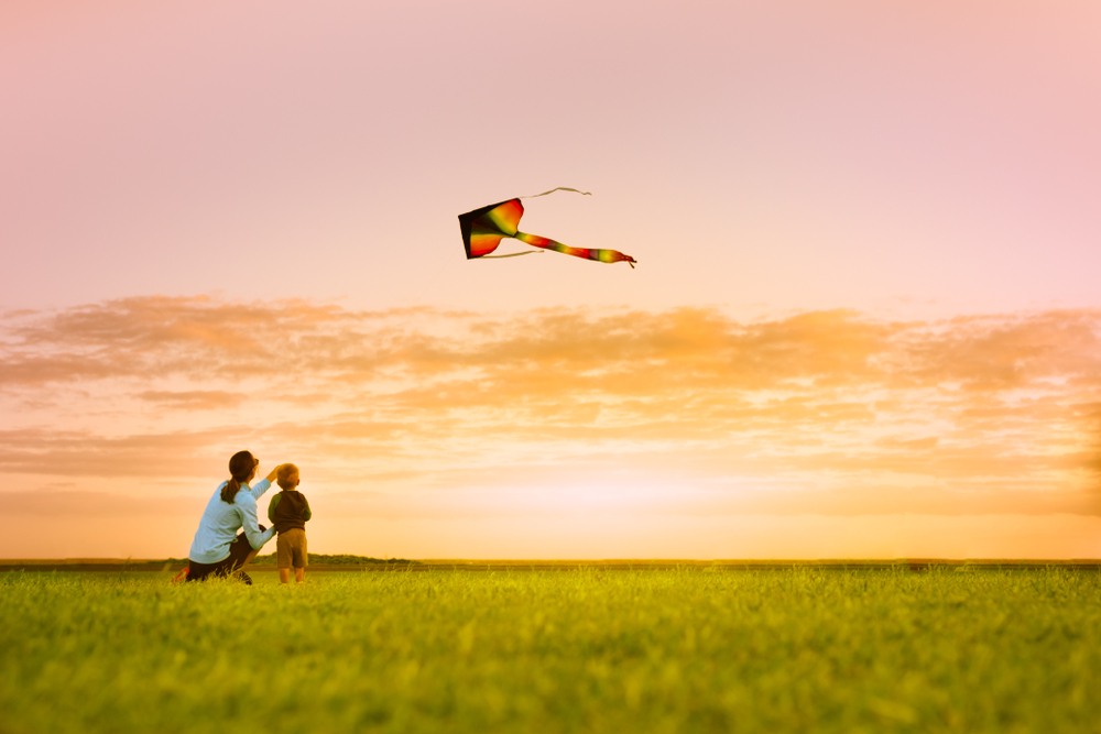 Mother and Child Playing with a Kite in the Sunset | Consider Using your Savings