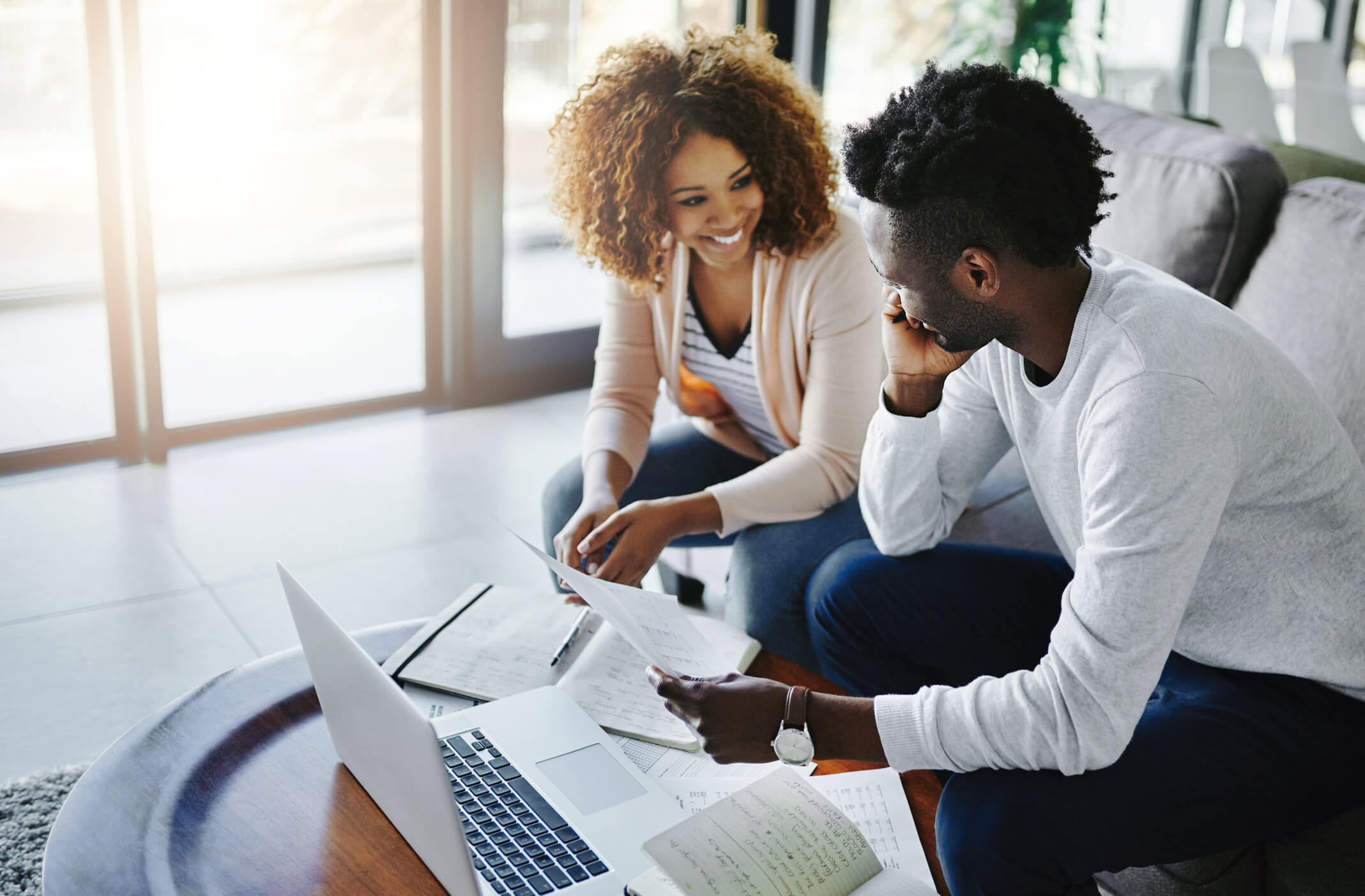 Two People Smiling Whilst Holding Documents | Creating a Budget Plan