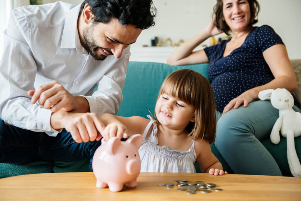 Pregnant Woman, Adult Male and Child Placing Coins in a Piggy Bank | Building up your Credit History